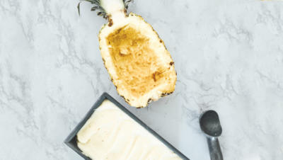 homemade ice cream tub next to carved out halved pineapple
